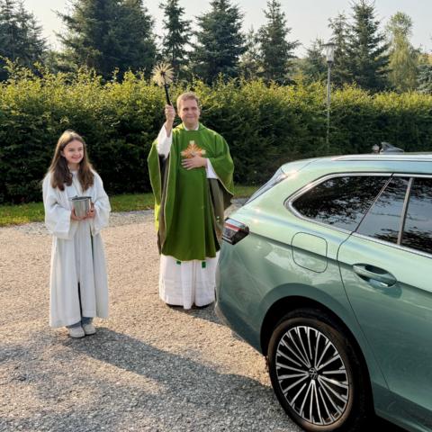 Pfarrer Detlef Pötzl besprengt anlässlich der Fahrzeugsegnung ein Auto mit Weihwasser.